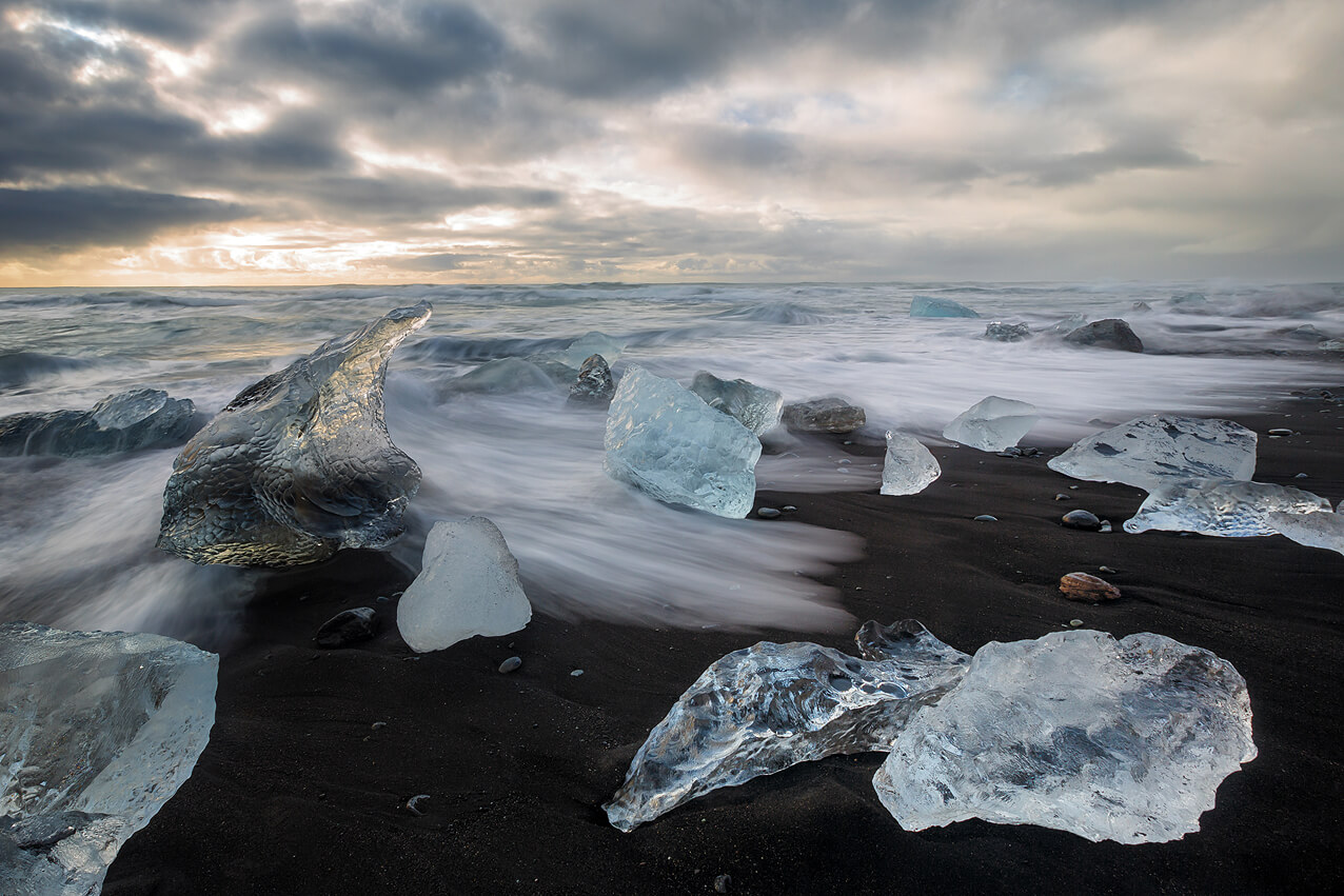 Langzeitbelichtung am schwarzen Lavastrand mit Eisblocken auf Island