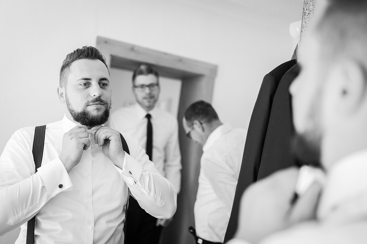 Der Bräutigam bindet sich die Fliege vor dem Spiegel