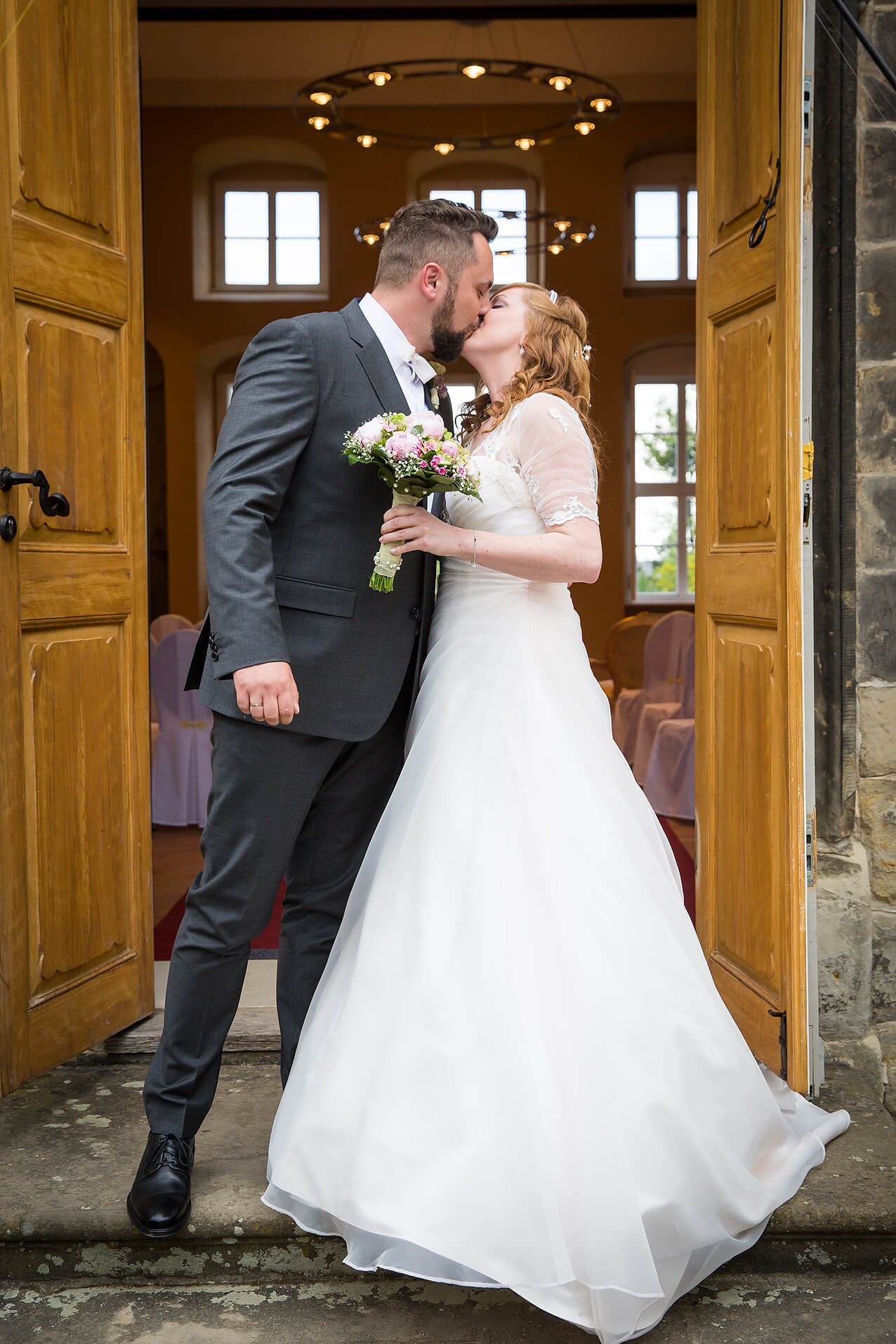 Das Brautpaar küsst sich vor dem Standesamt