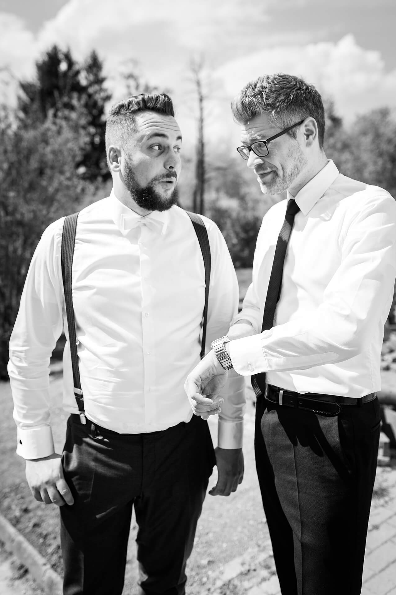 Bräutigam und Trauzeuge blicken während der letzten Hochzeitsvorbereitungen auf die Uhr