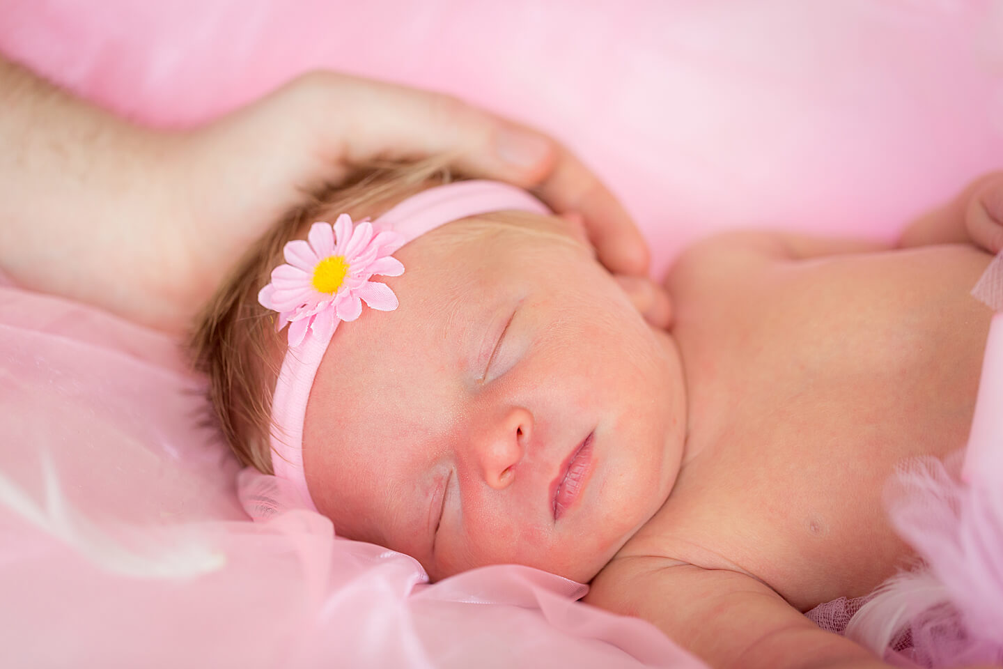 Schlafendes Neugeborenes mit der schützenden Hand das Vaters am Köpfchen