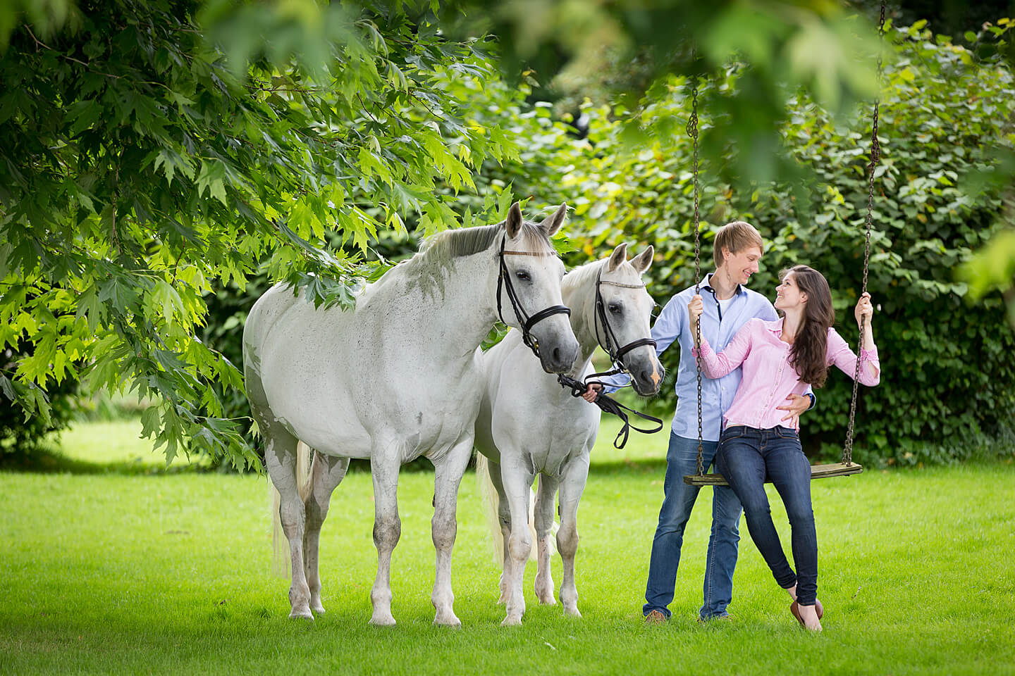 Junges Paar auf der Schaukel beim Fotoshooting mit zwei Pferden