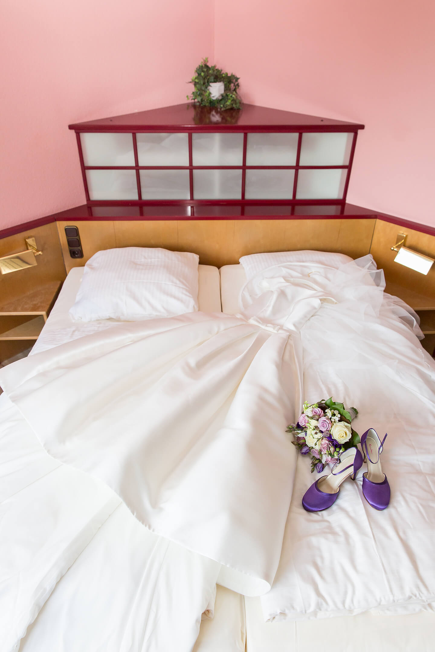 Brautkleid und Brautstrauss auf dem Hotelbett im Hotel Holst