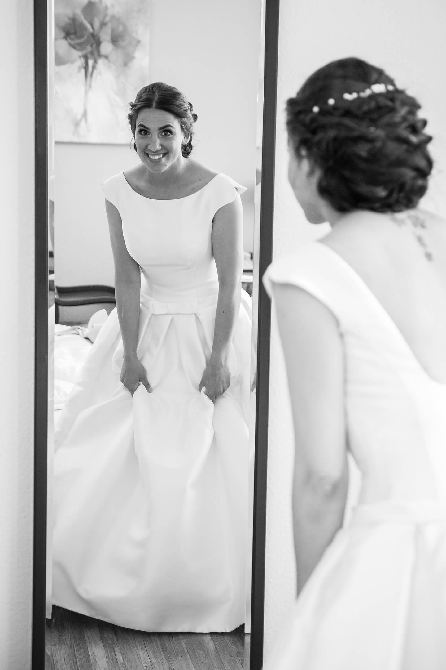 Braut im Hochzeitskleid schaut in den Spiegel