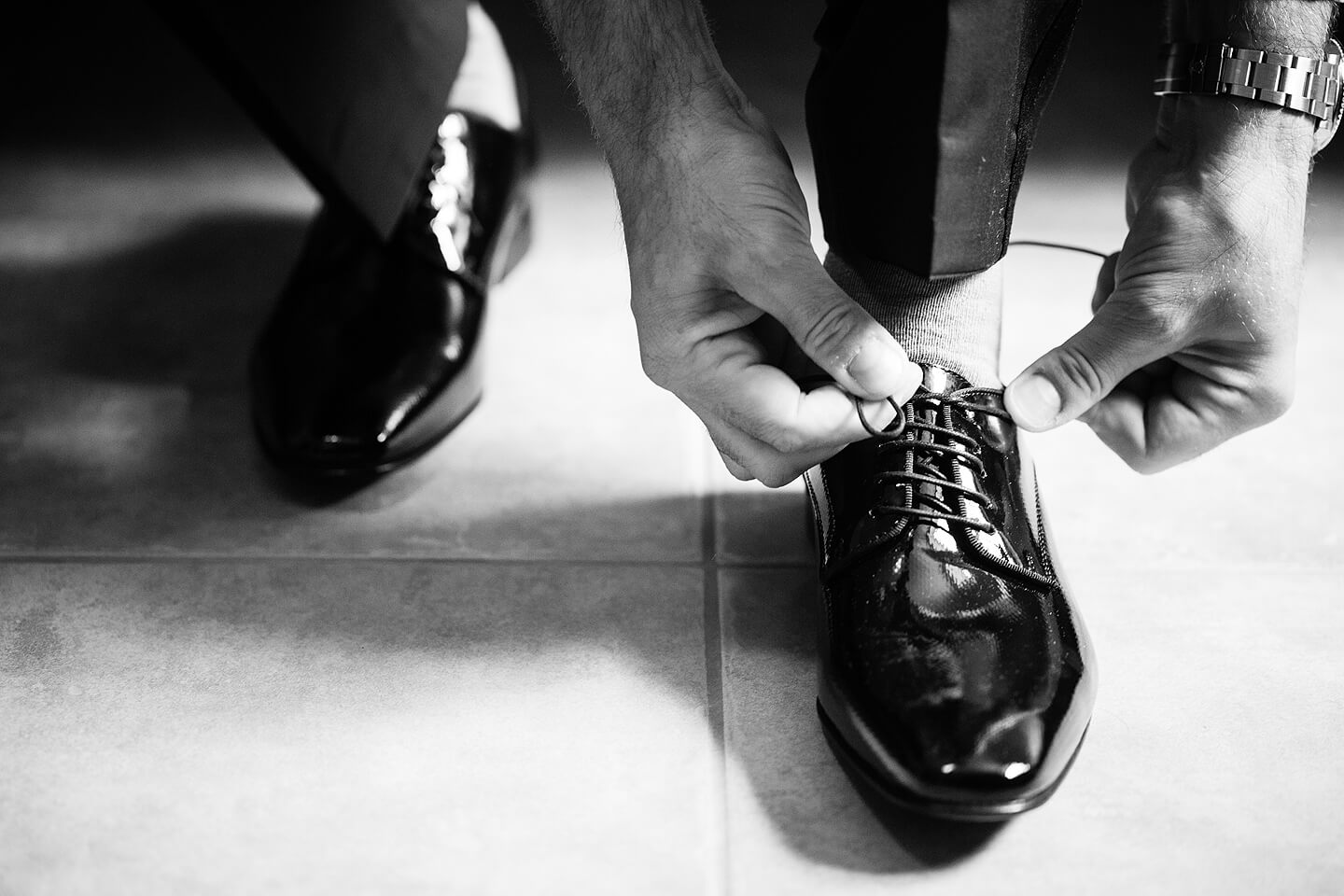 Detailaufnahme vom zuschnueren der Hochzeitsschuhe des Bräutigams
