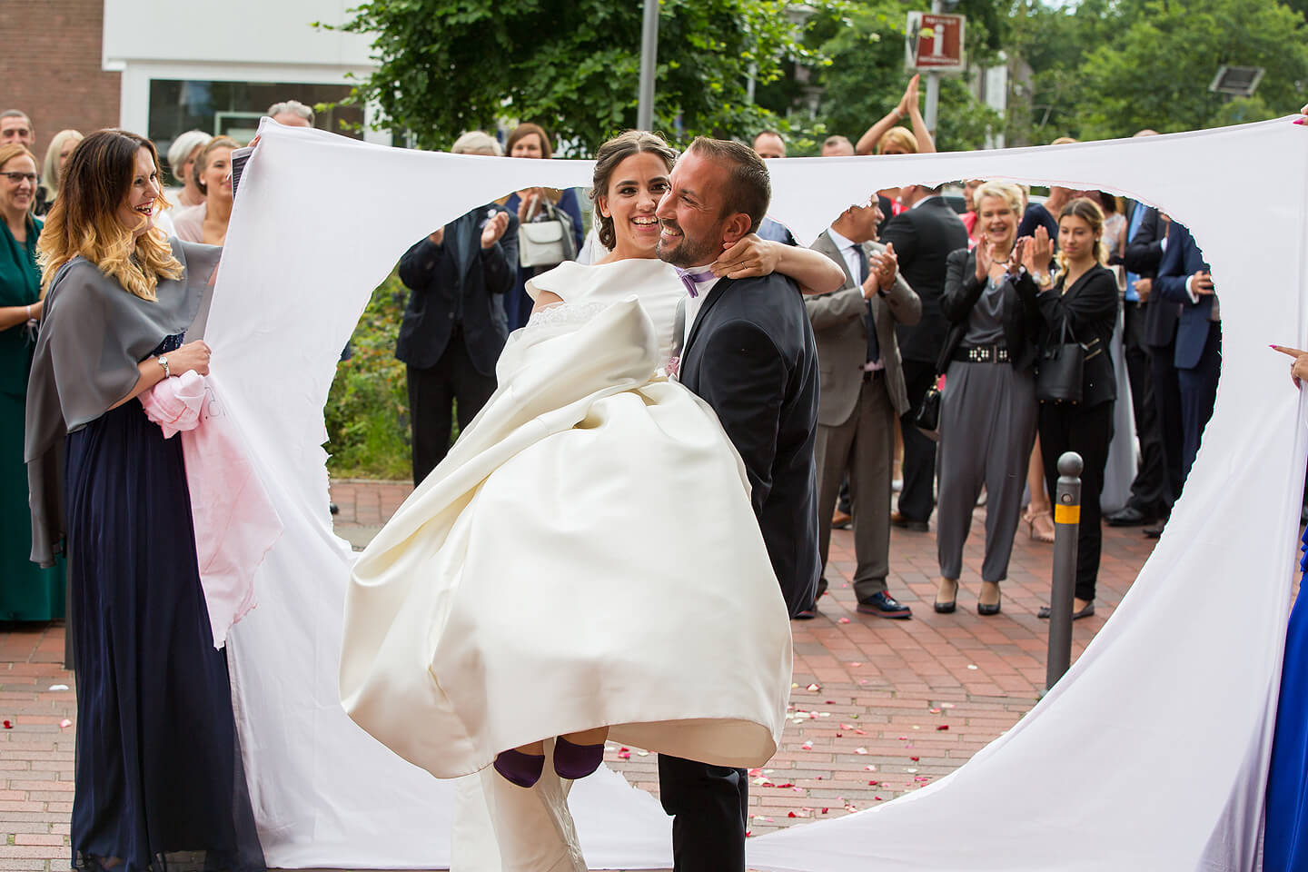 Bräutigam trägt Braut durchs ausgeschnittene Herz