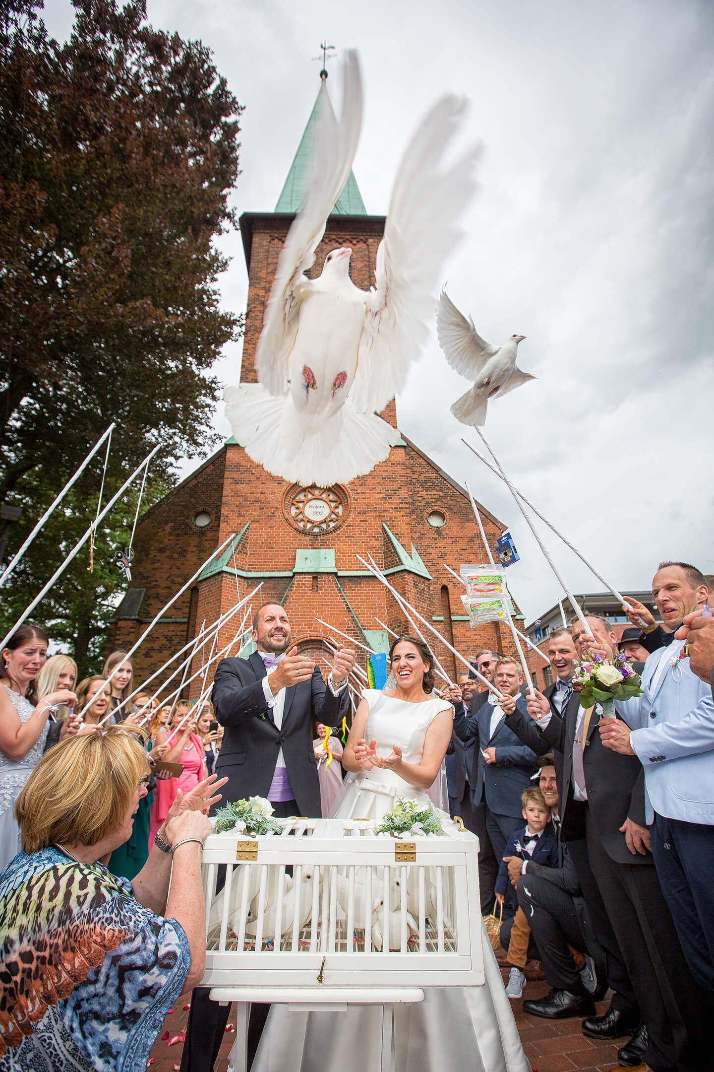 Brautpaar lässt weisse Tauben nach der Hochzeit fliegen