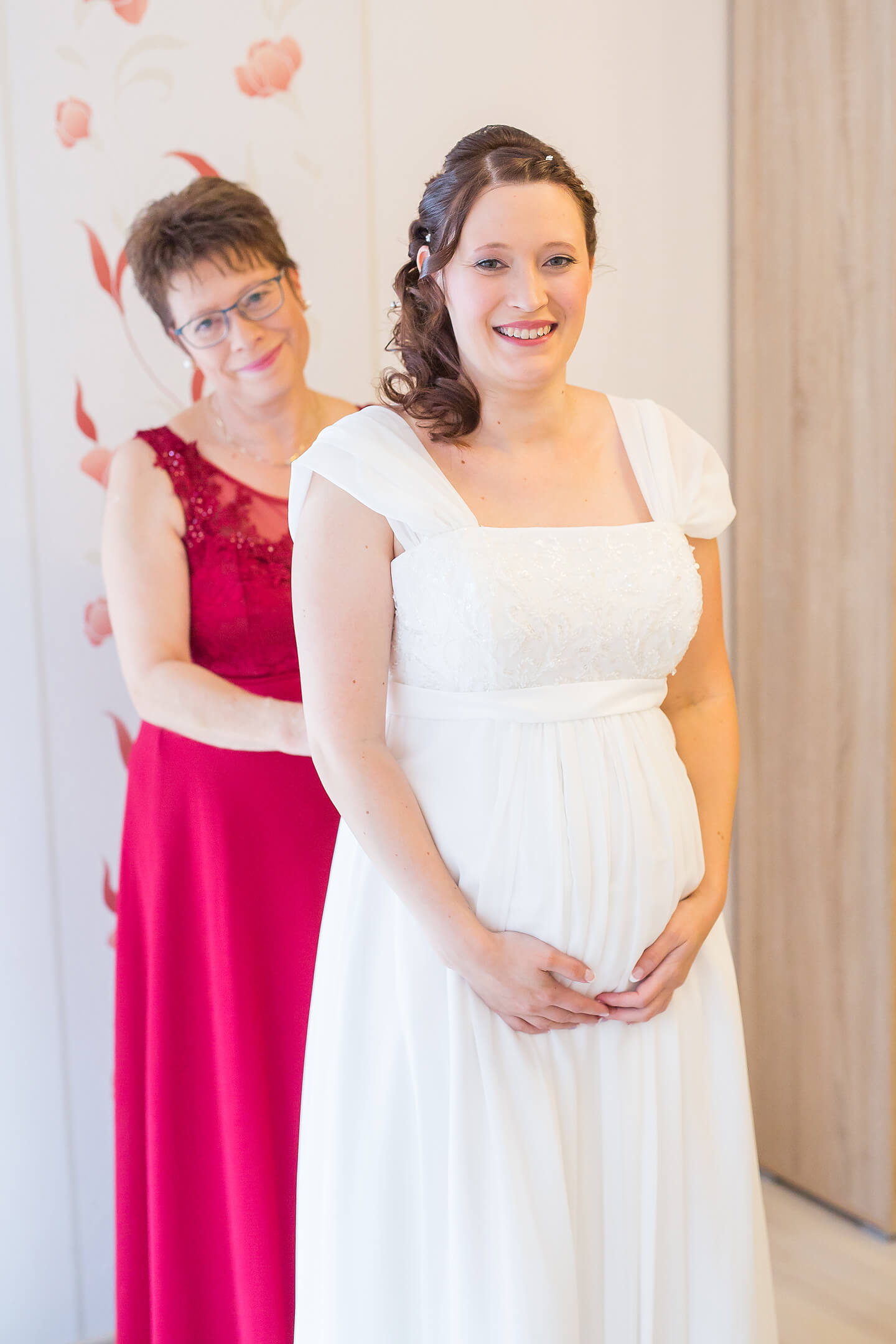 Brautmutter schnürt während einer Hochzeitsreportage das Brautleid