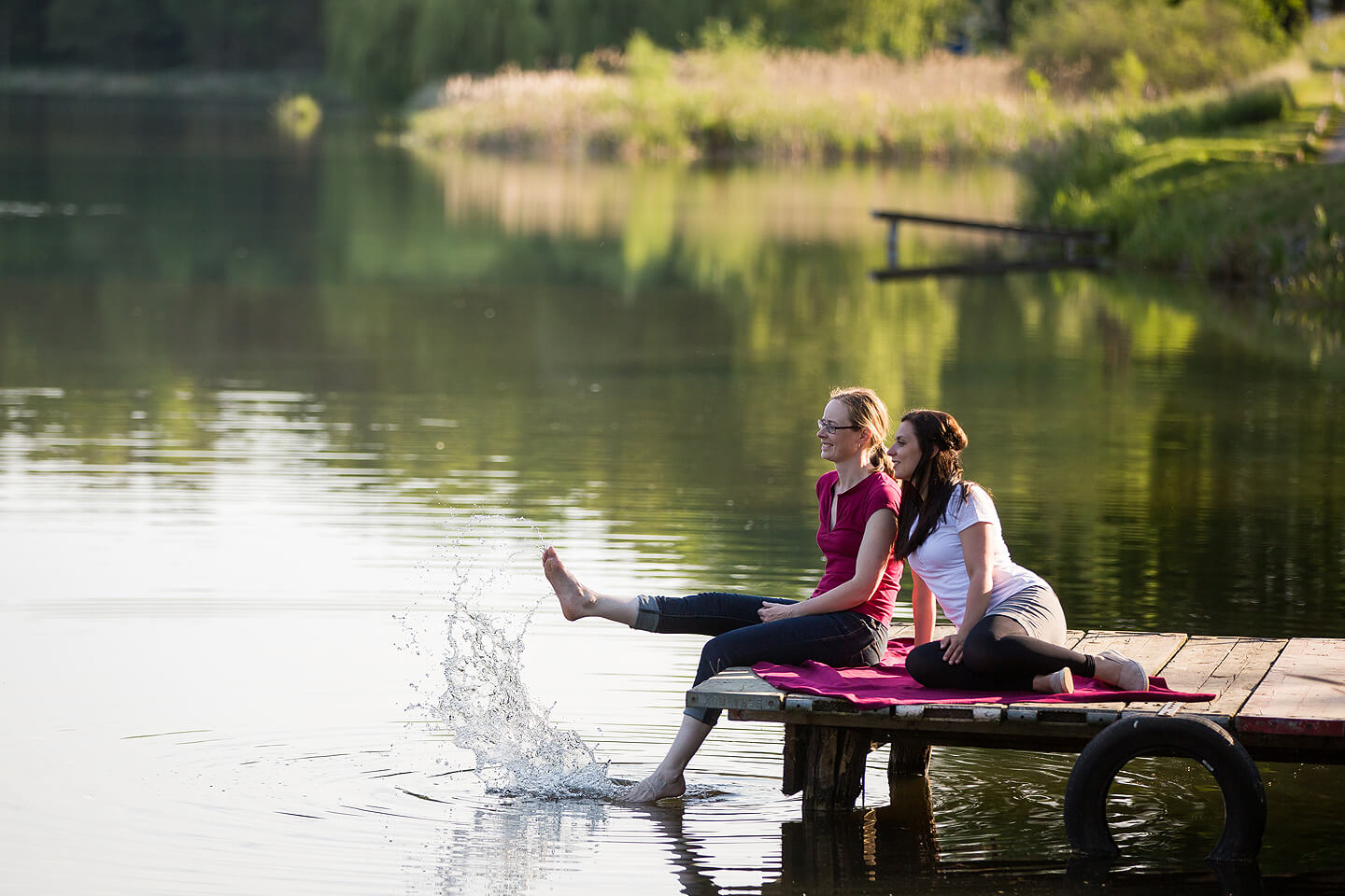 Stimmungsfoto von zwei jungen Damen auf einem Steg am See