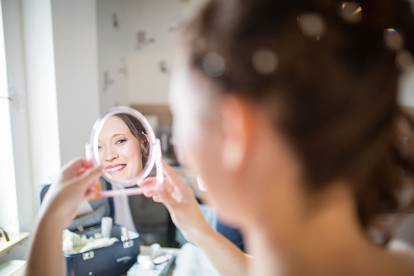 Braut schaut glücklich in den Handspiegel