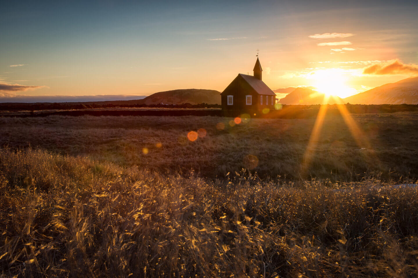 Die schwarze Kirche bei Budir in der untergehenden Sonne mit reichlich Lens flares im Bild