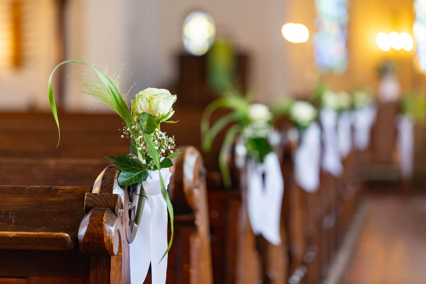 Blumengestecke als Schmuck an den Holzbänken in der Kirche