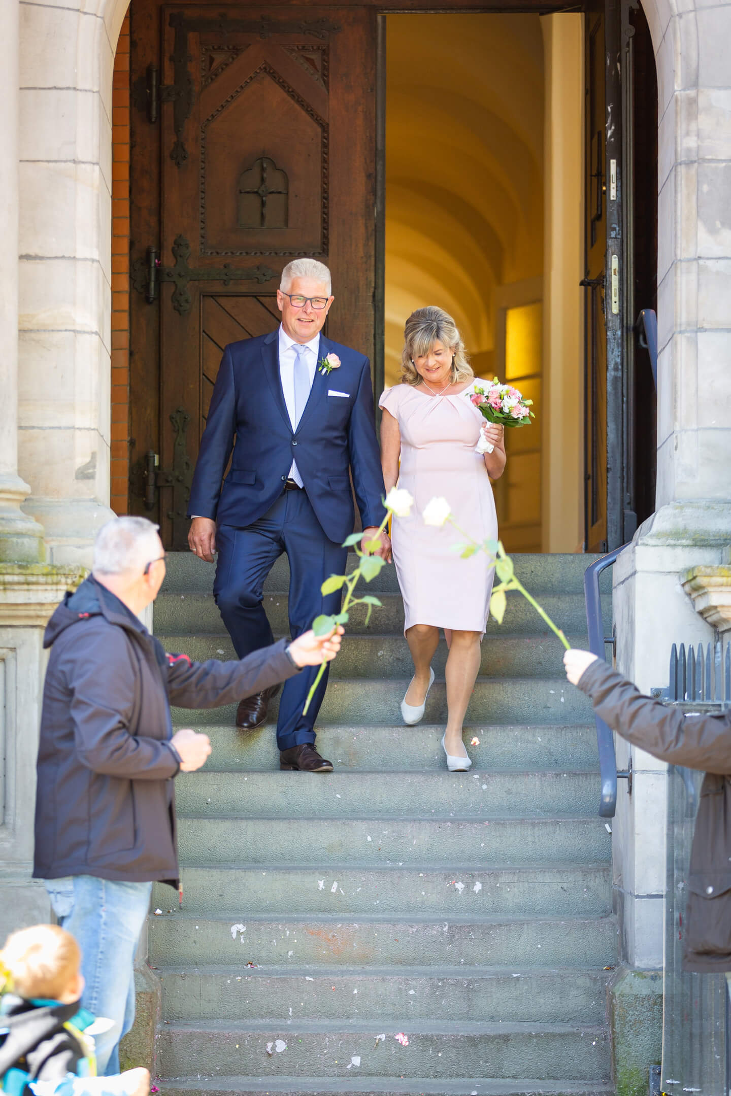 Hochzeitspaar schreitet aus dem Standesamt die Stufen herunter