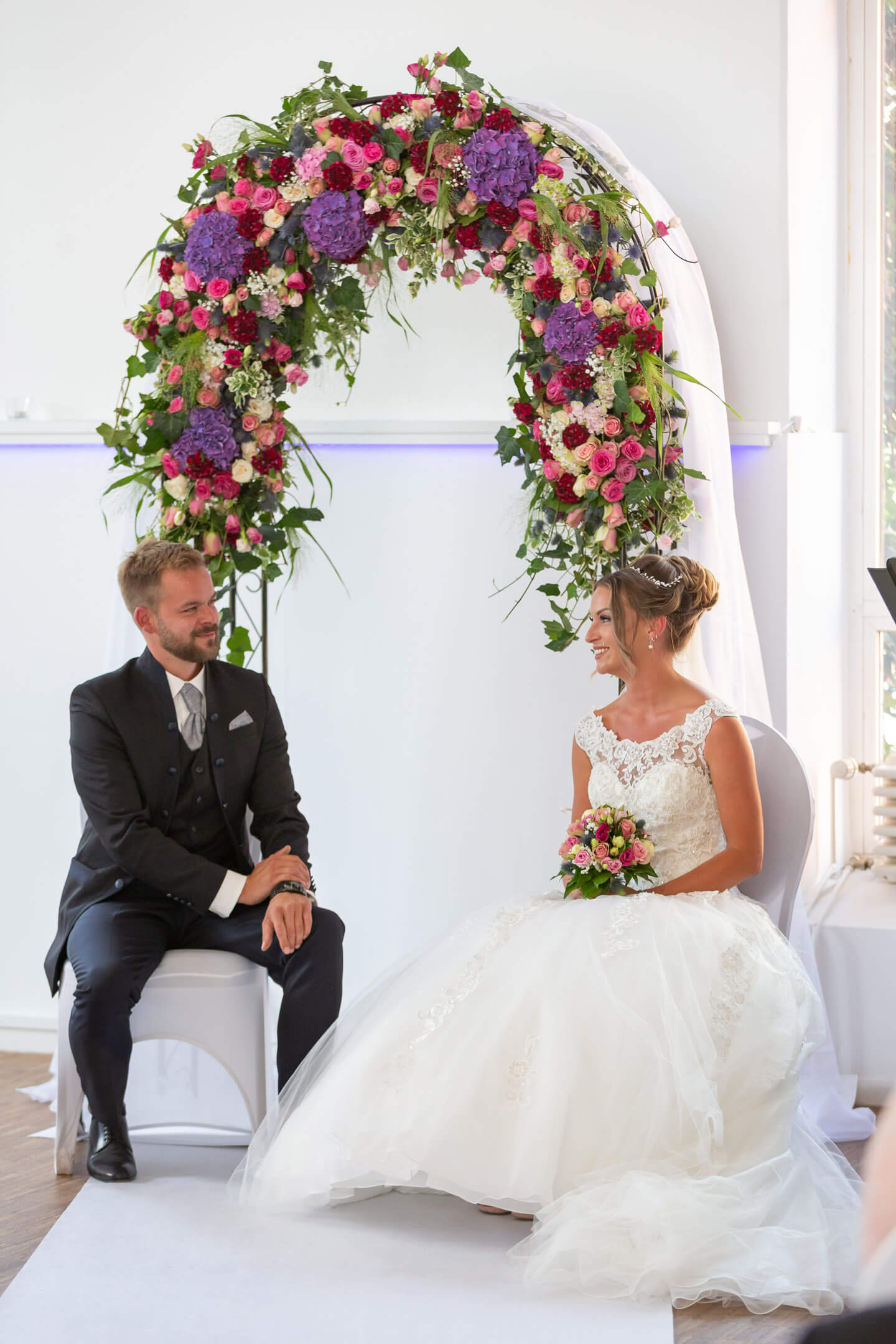 Hochzeitspaar mit Blumenbogen bei ihrer Hochzeit in der alten Friesenbrauerei