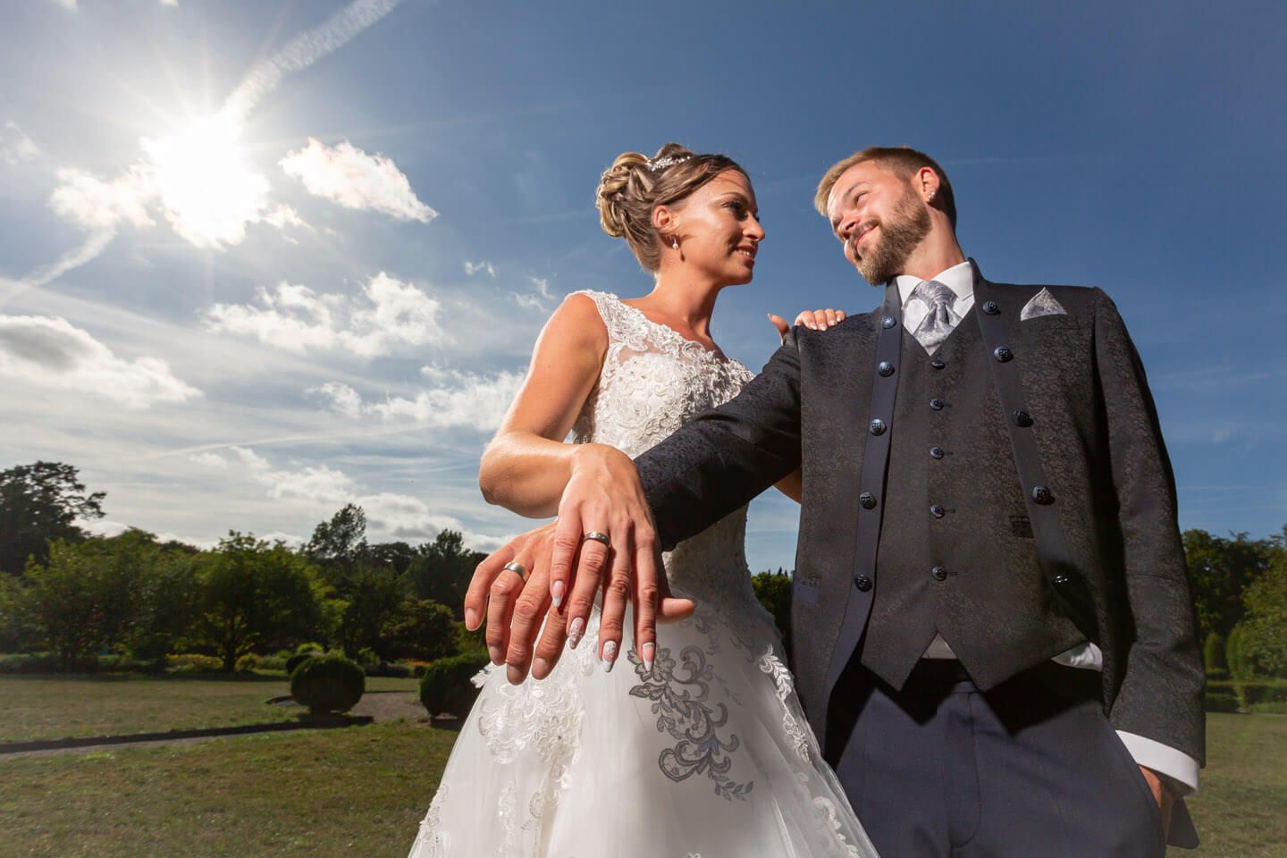 Brautpaar zeigt die Eheringe im Gegenlicht