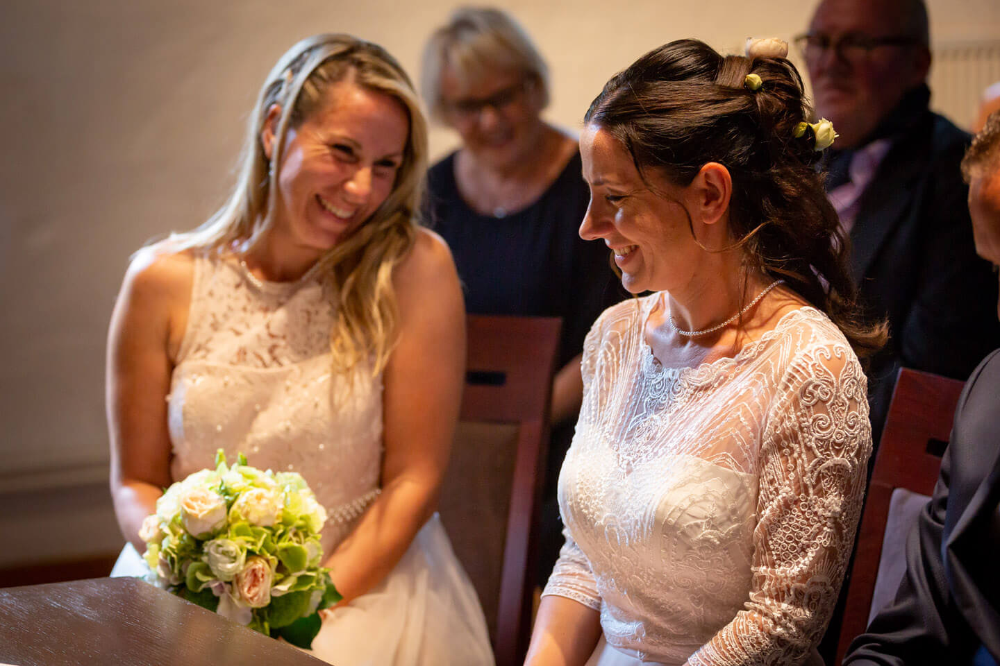 Trauzeugin lacht Braut im Standesamt an