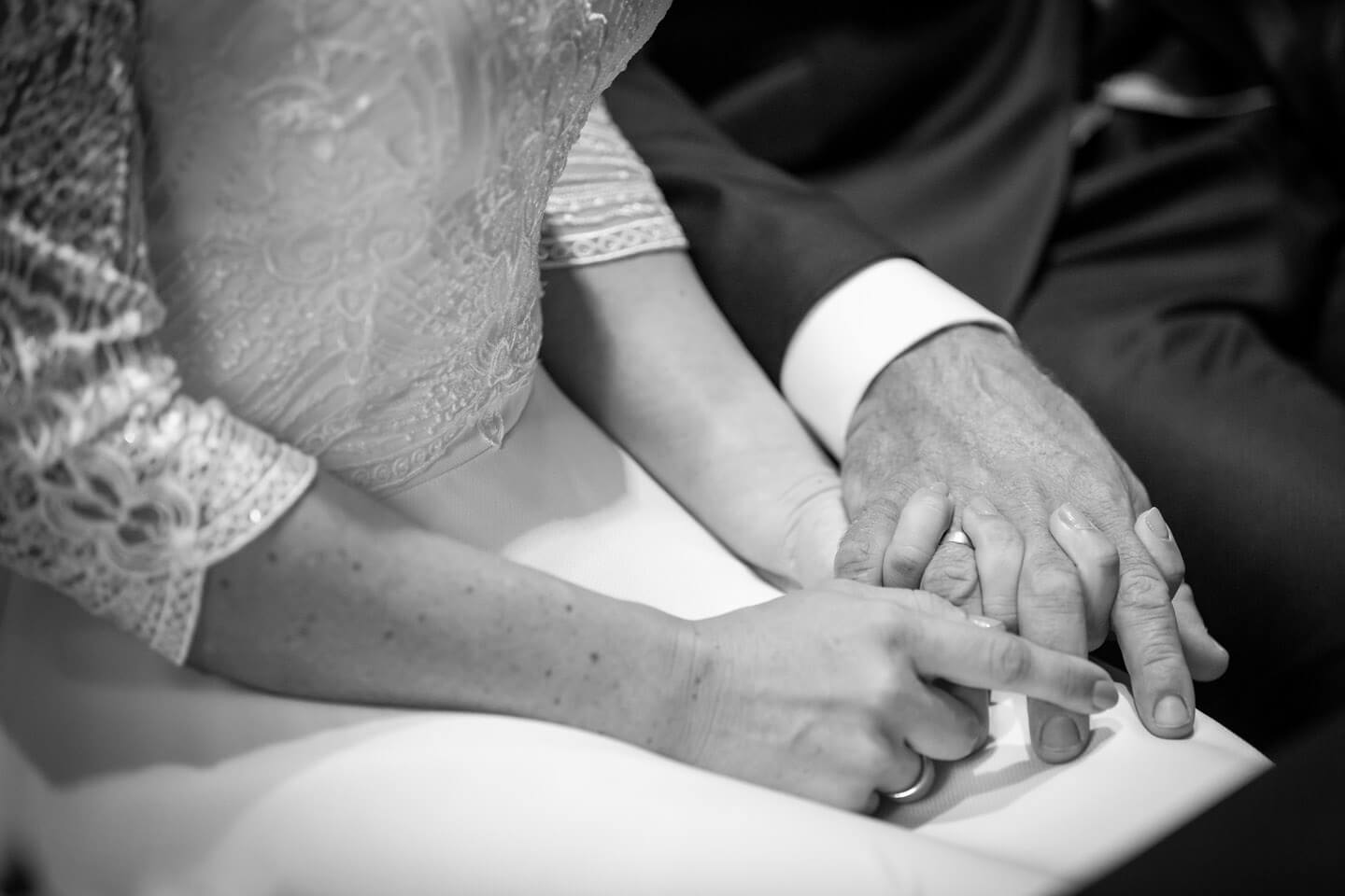 Brautpaar hält sich die Haende während der Hochzeit in der Trittauer Mühle