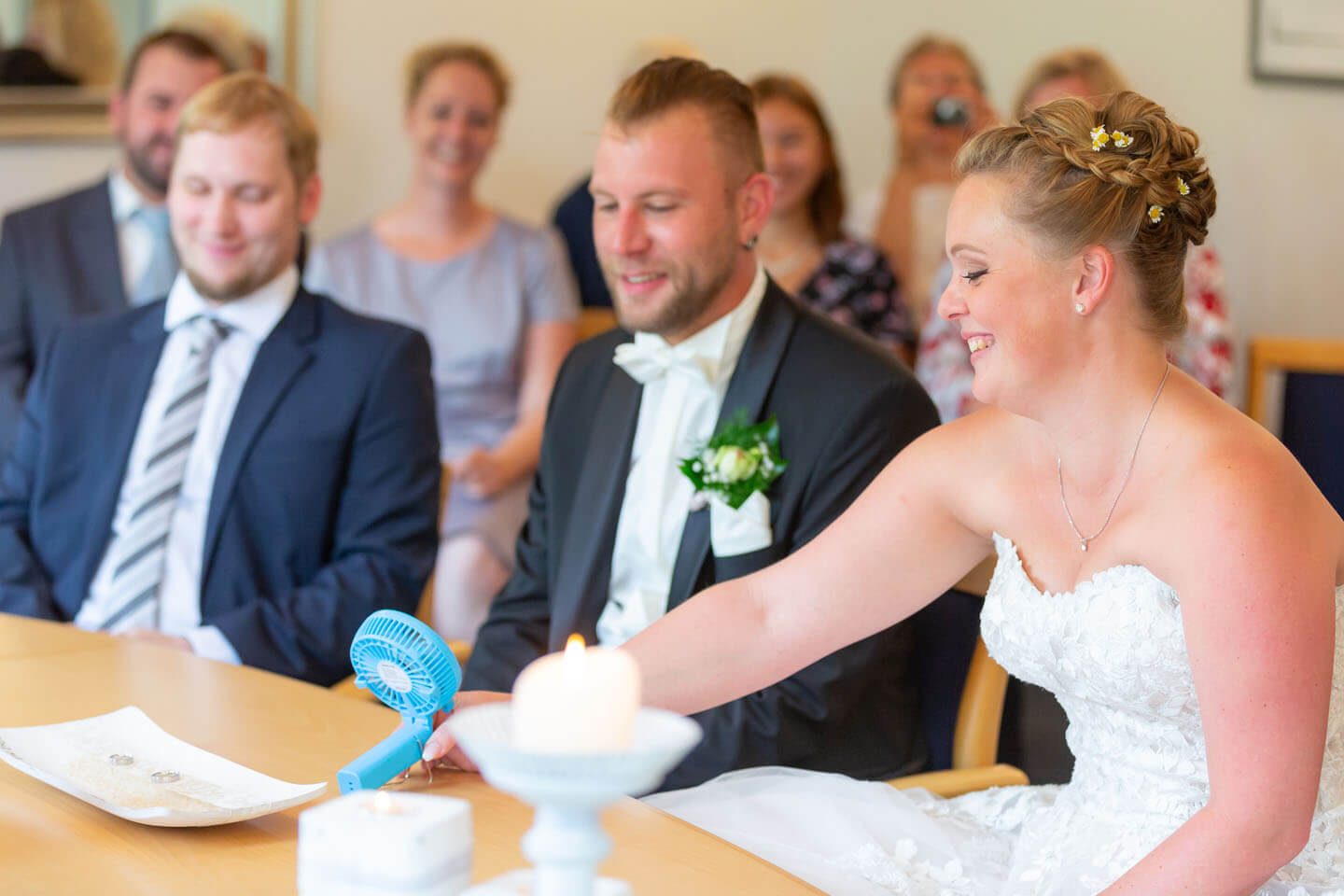 Braut schiebt den kuehlenden Ventilator zum Gatten hinueber