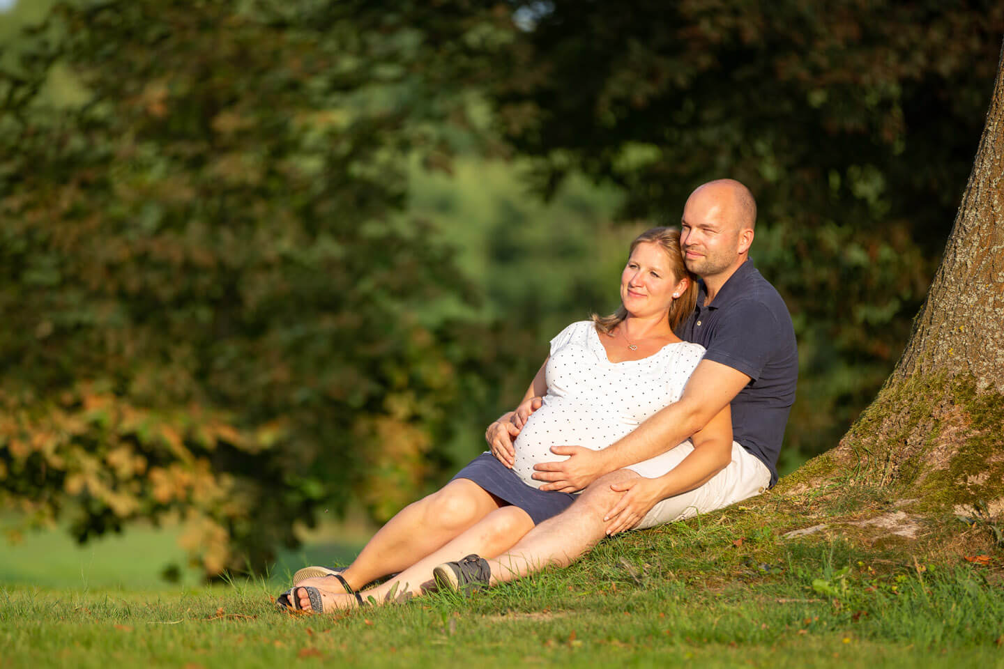 Schwangerschaftsfoto des Fotografen Florian Laeufer aus Hamburg. Paar liegt an Baum gelehnt in der späten Abendsonne