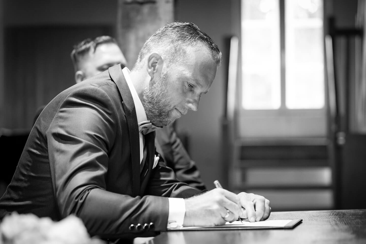 Braeutigam unterschreibt die Heiratsurkunde in der Trittauer Wassermuehle