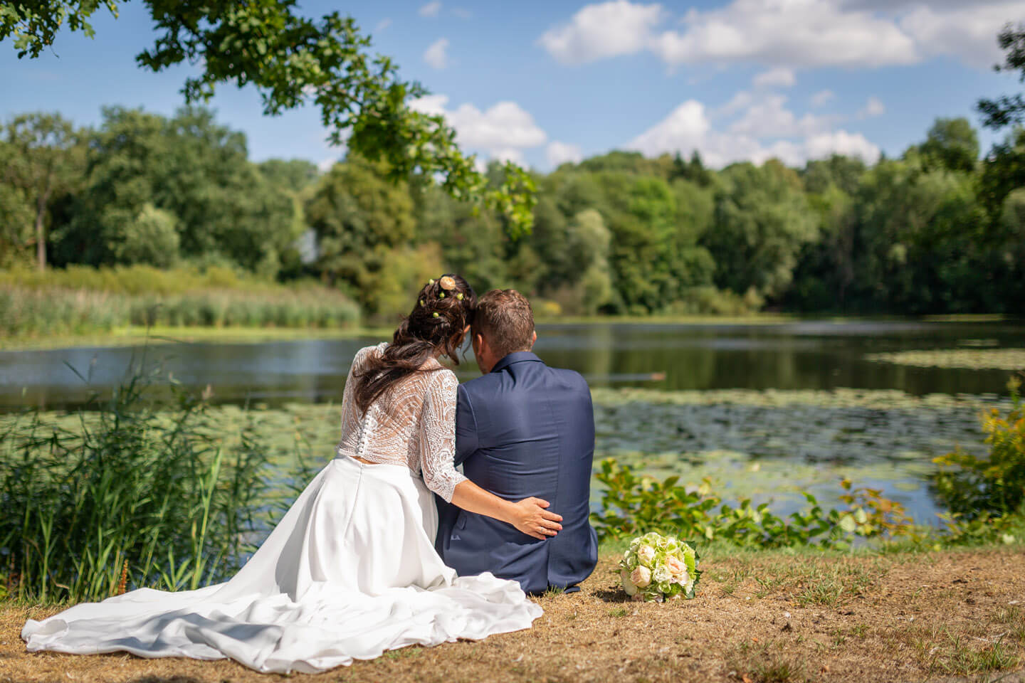 Hochzeitspaar blickt vertraeumt auf den Trittauer Muehlenteich