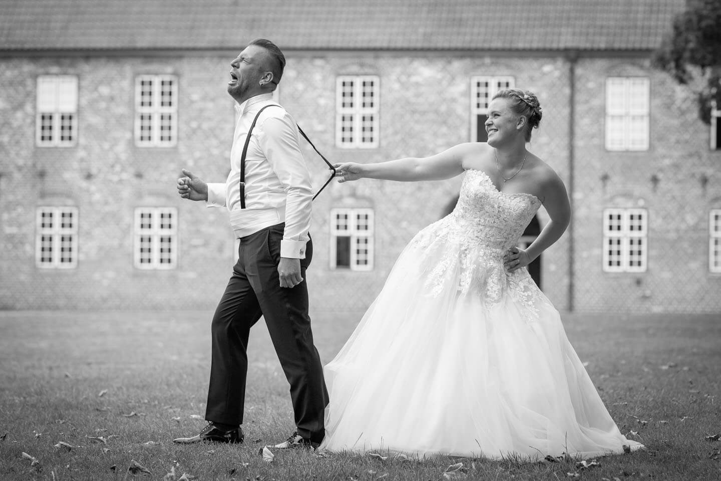 Witziges Hochzeitsfoto - Braut hält Mann am Hosenträger fest