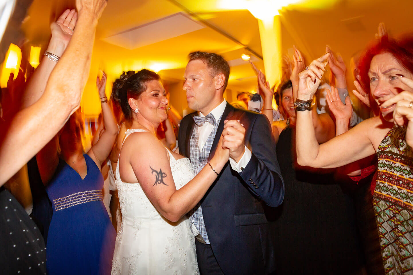 Hochzeitspaar eng von Gästen umringt auf der Tanzfläche.