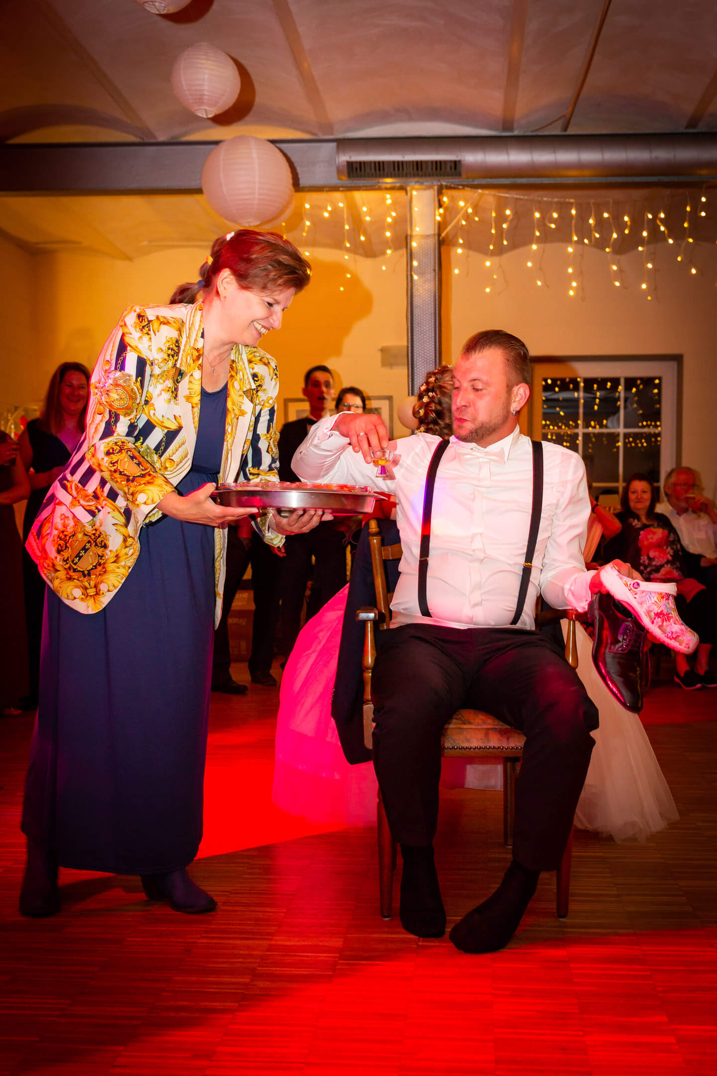 Trinkspiel auf Hochzeitsfeier. Braeutigam bekommt einen Kurzen serviert.