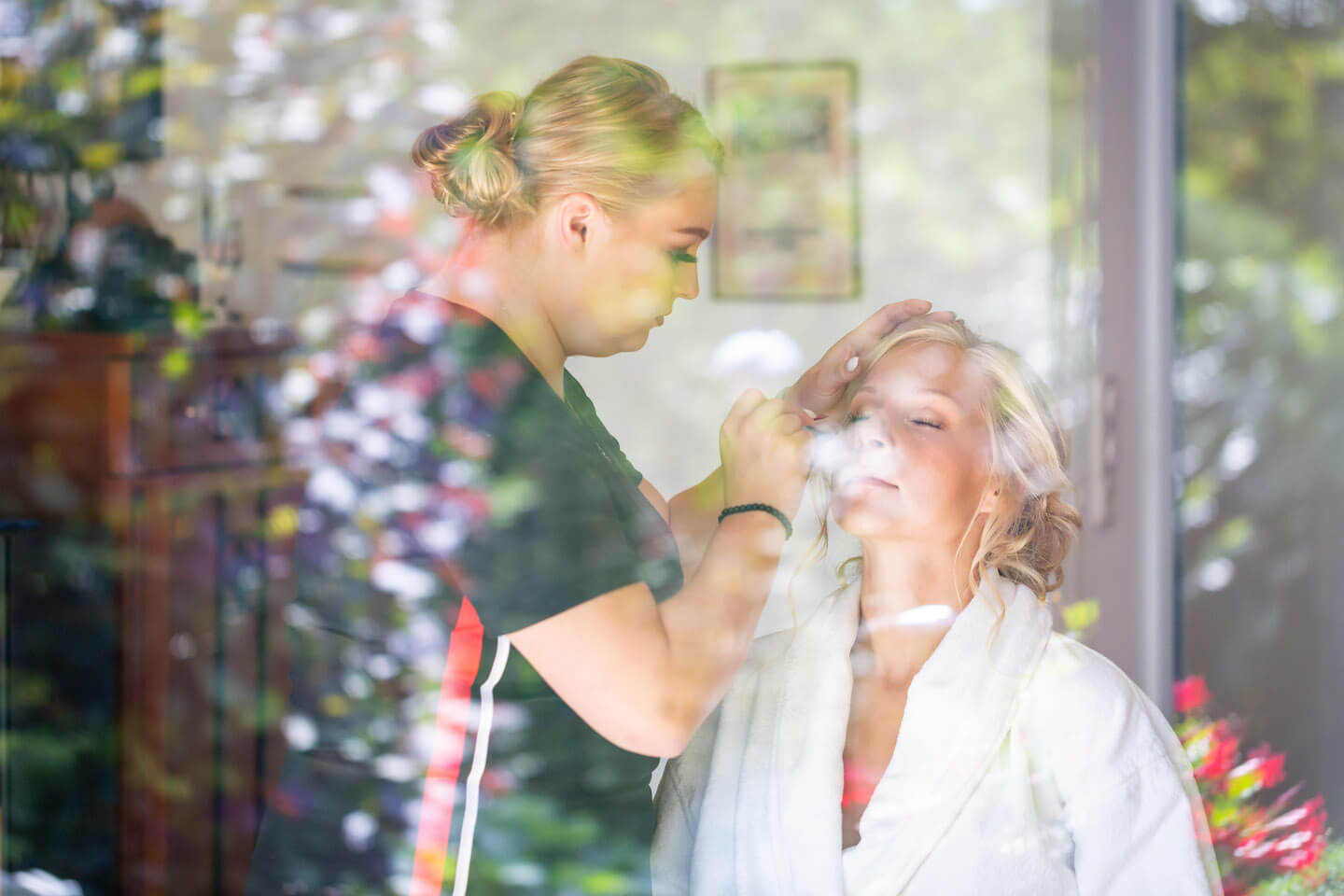 Durchs Fenster fotografiert: Braut mit Visagistin