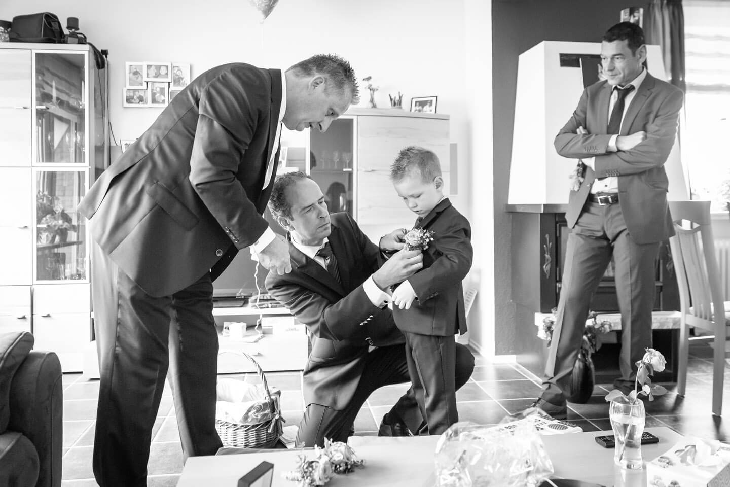 Dem Kind des Brautpaares werden die Blumen an den Anzug gesteckt