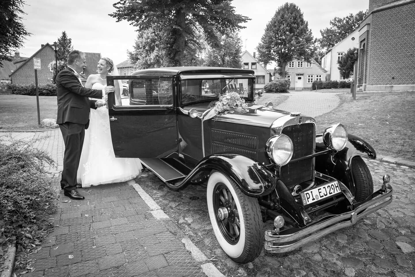Brautpaar steigt ins historische Auto ein