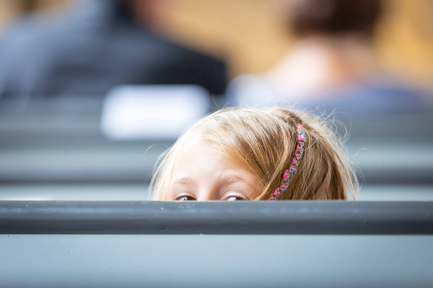 Maedchen schaut bei einer Trauung vorsichtig über die Kirchenbank in die hinteren Reihen
