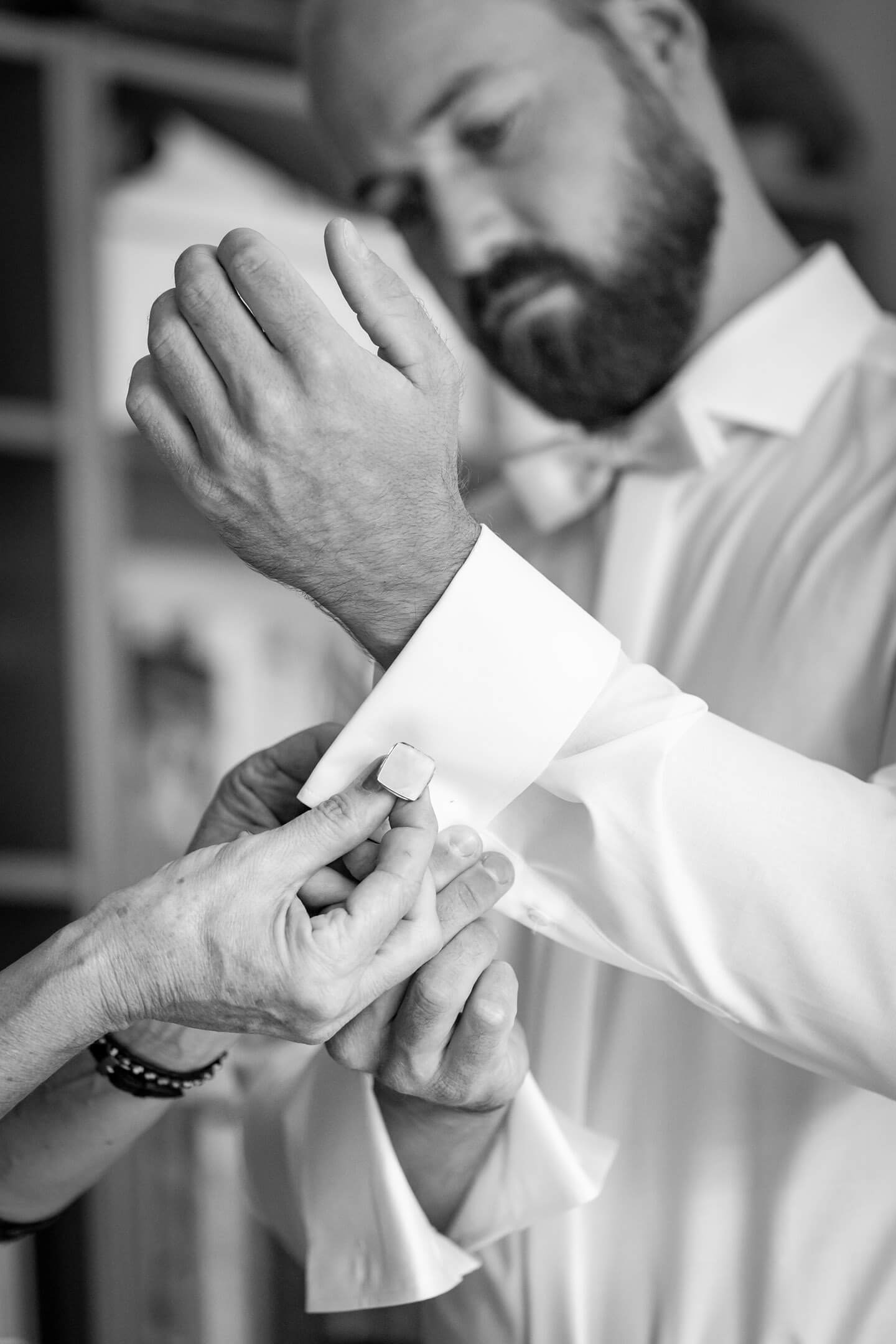 Manschettenknopf wird am weißen Hemd geschlossen.