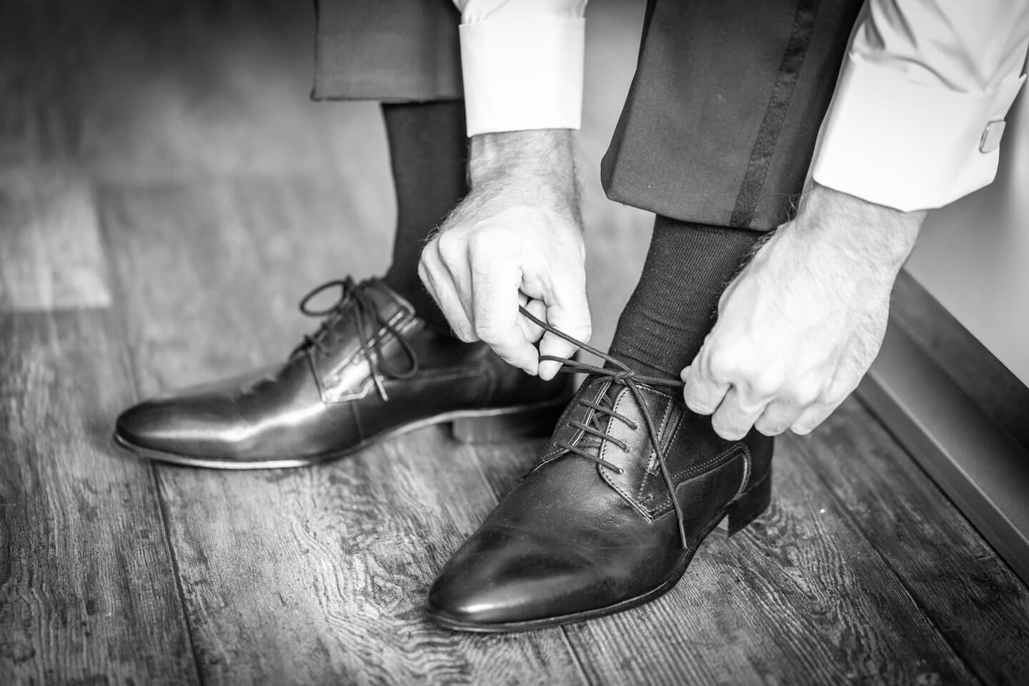 Braeutigam schnuert die Schuhe zu