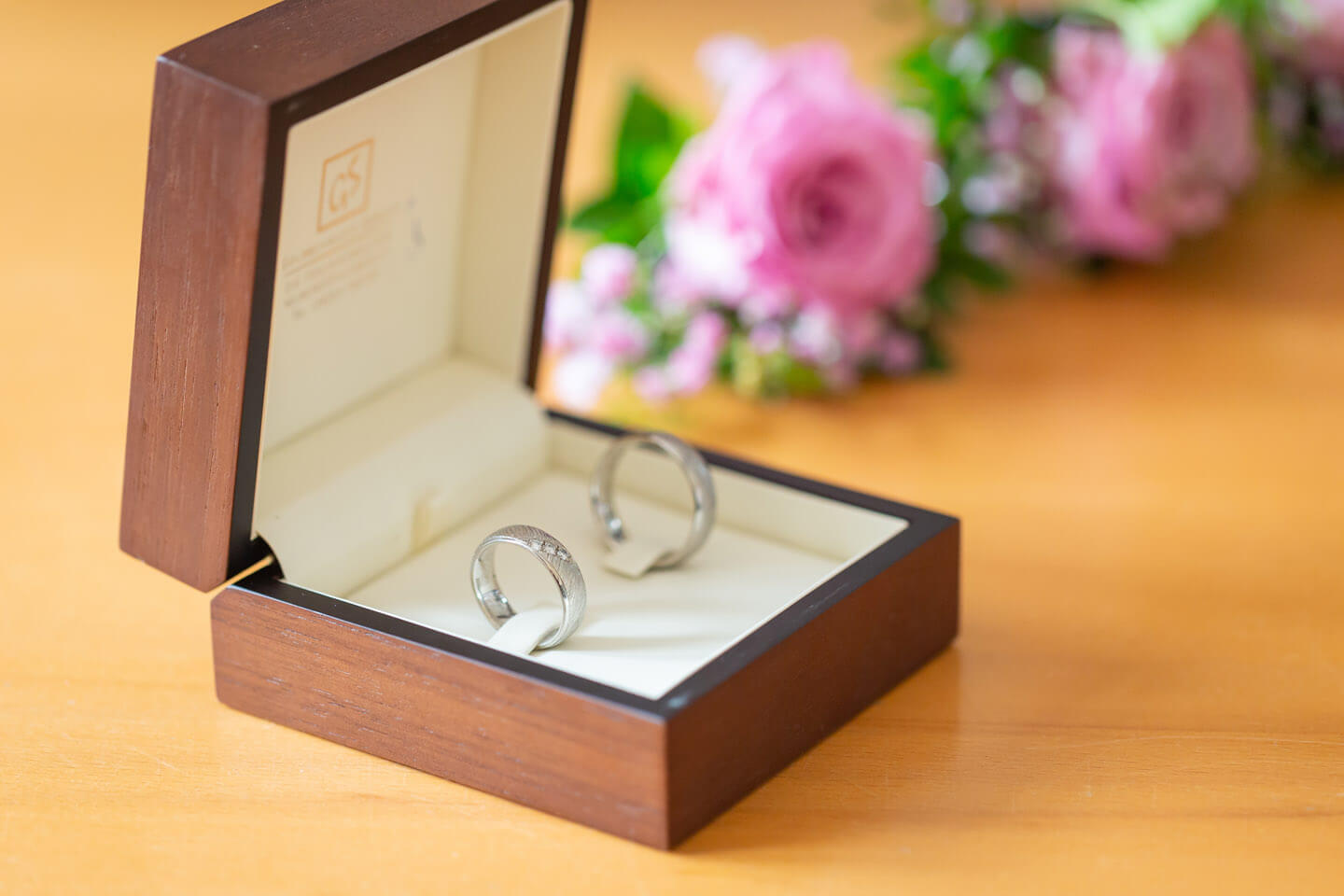 Trauringe mit Blumenschmuck im Hintergrund