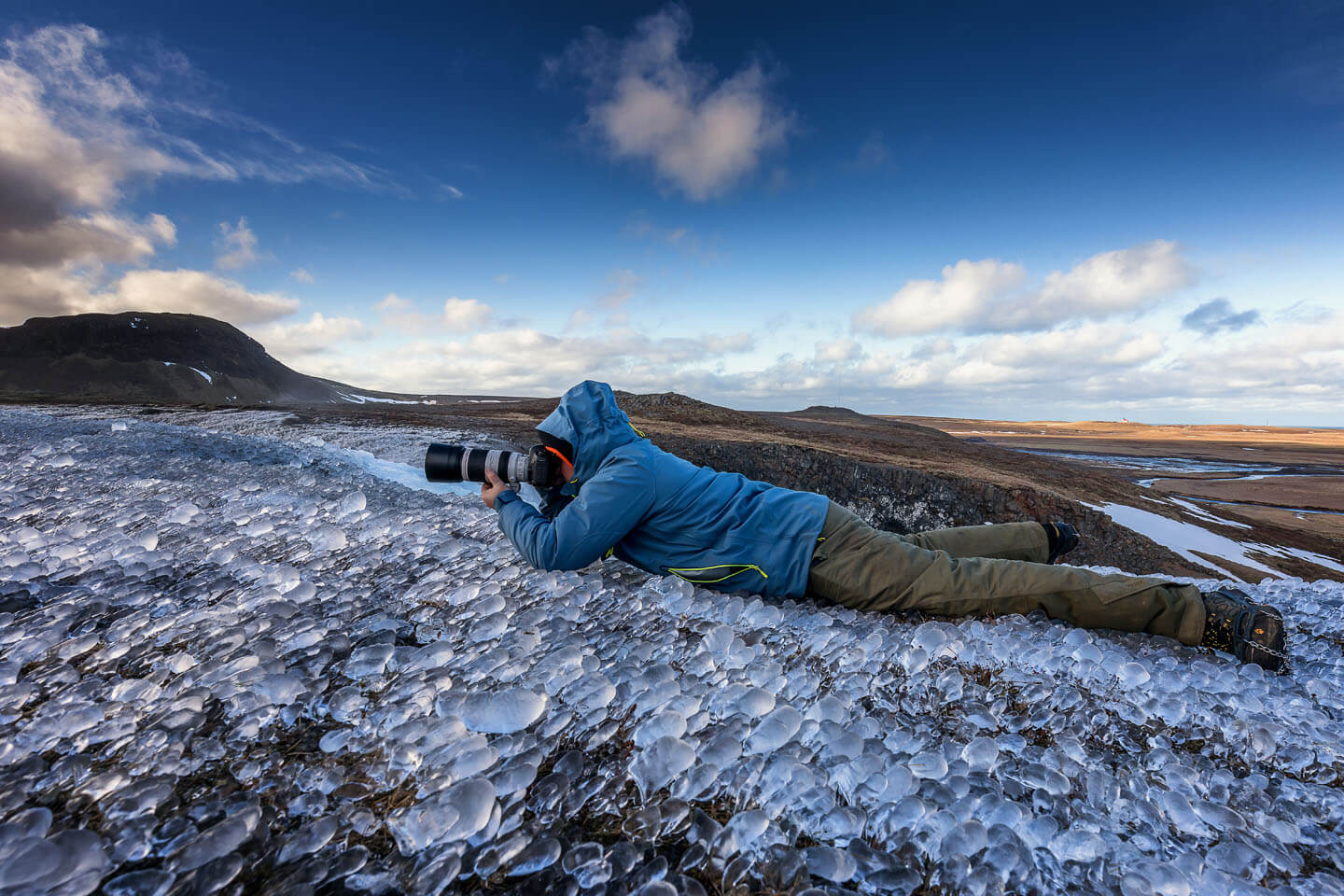 Fotograf Florian Läufer liegt bäuchlings auf einer Eisfläche für eine schöne Perspektive