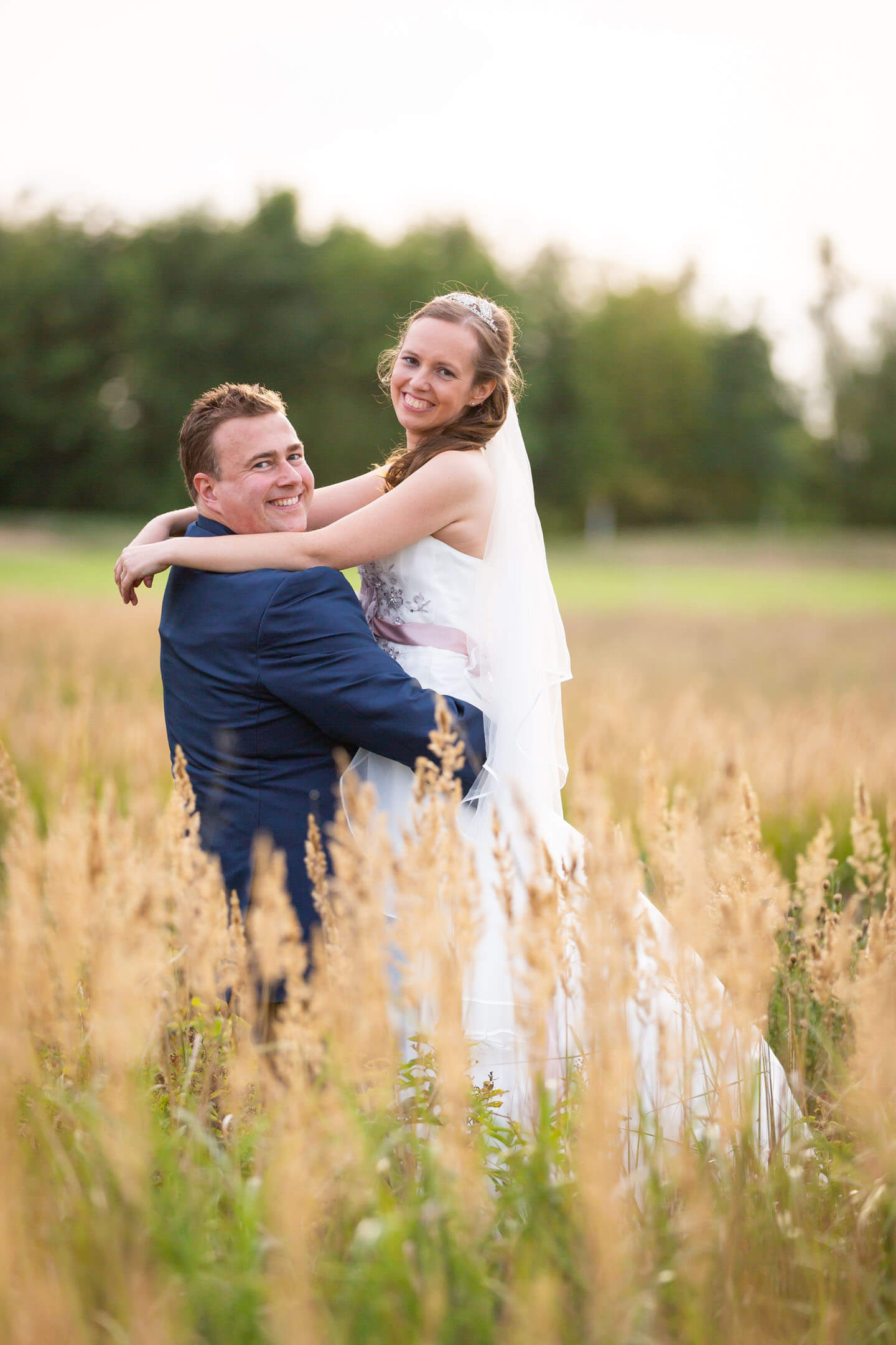 Hochzeitsshooting im Grünen. Mann hebt seine Frau hoch.