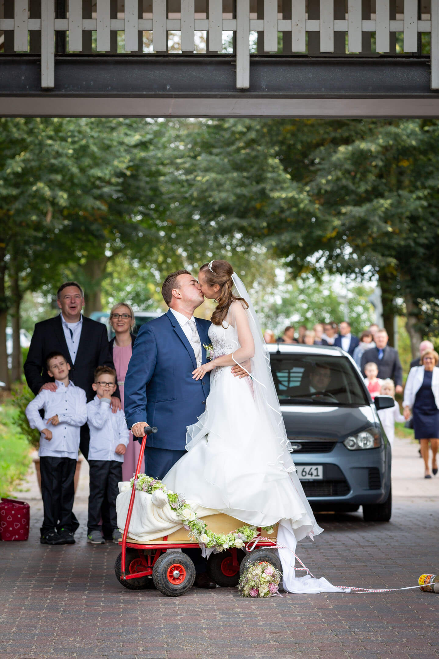 Brautpaar küsst sich, während die Braut im Bollerwagen steht