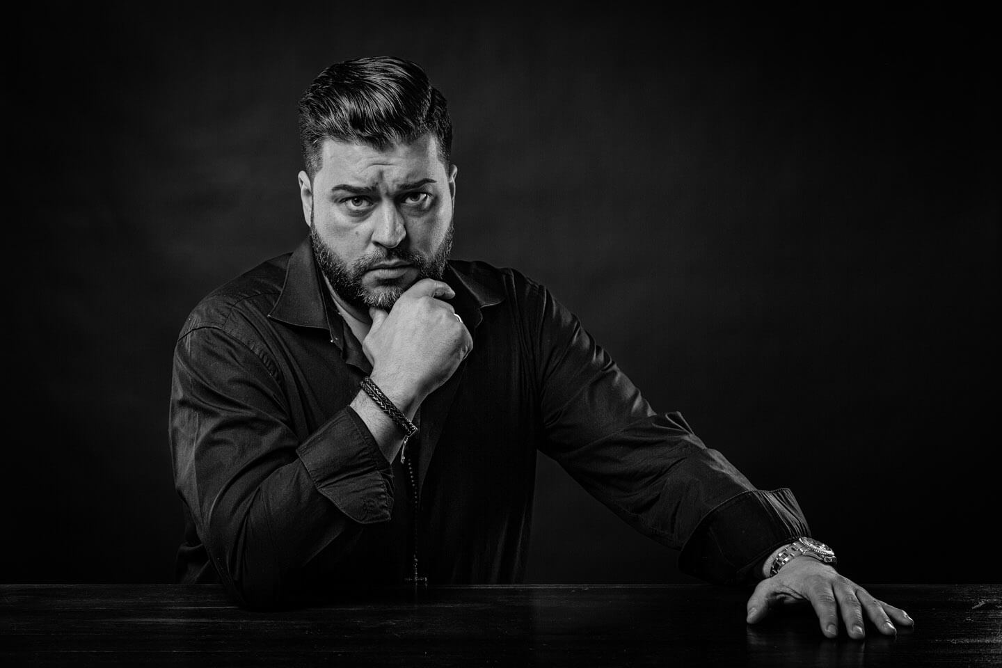 Portraitfoto Mann am Tisch in Schwarzweiss