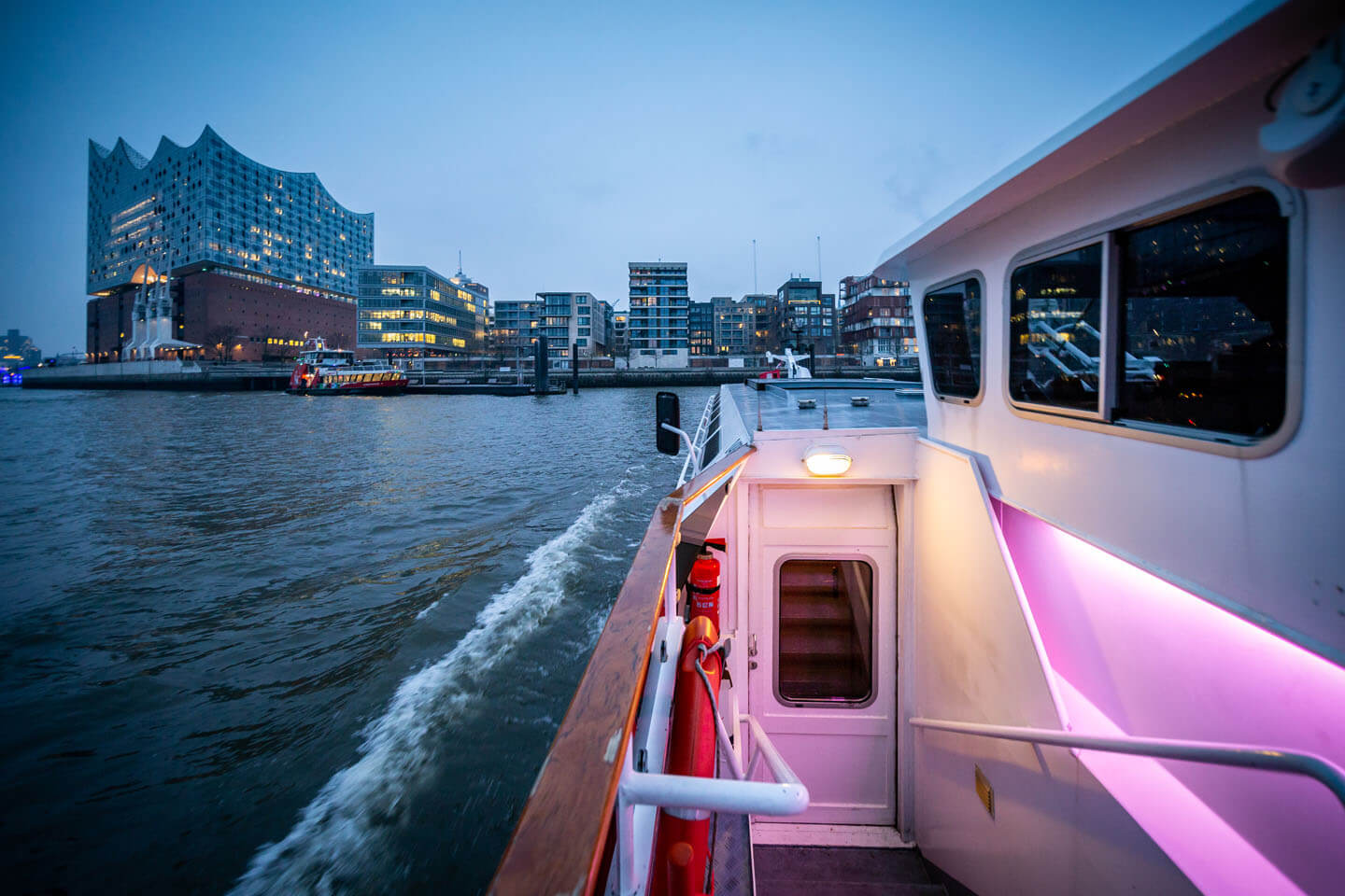 Barkasse steuert im hamburger Hafen auf die Elbphilharmonie zu