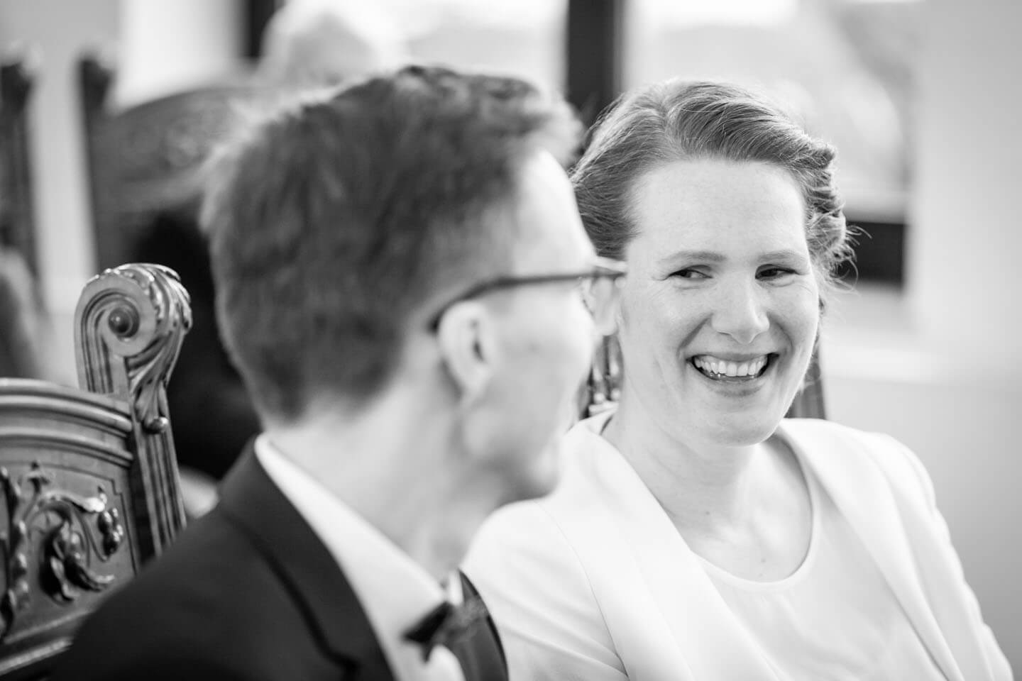 Braut lächelt Bräutigam an.