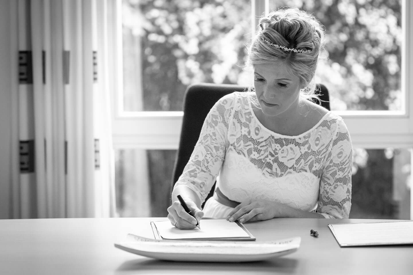 Festgehlten von dem Hochzeitsfotograf Florian Läufer aus Hamburg: Braut beim Unterschreiben der Trauurkunde