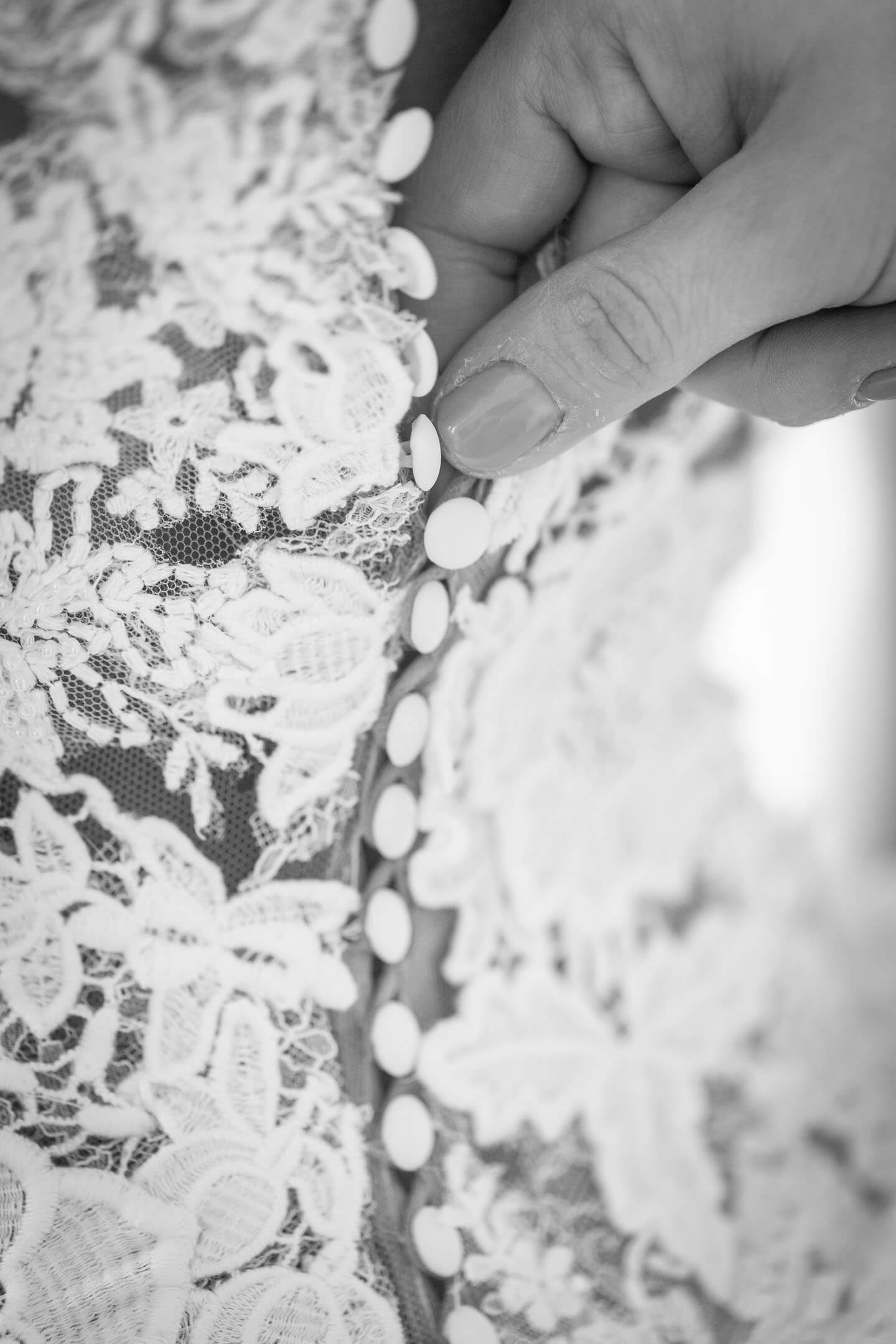 Zuknöpfen des Brautkleides beim Getting Ready.