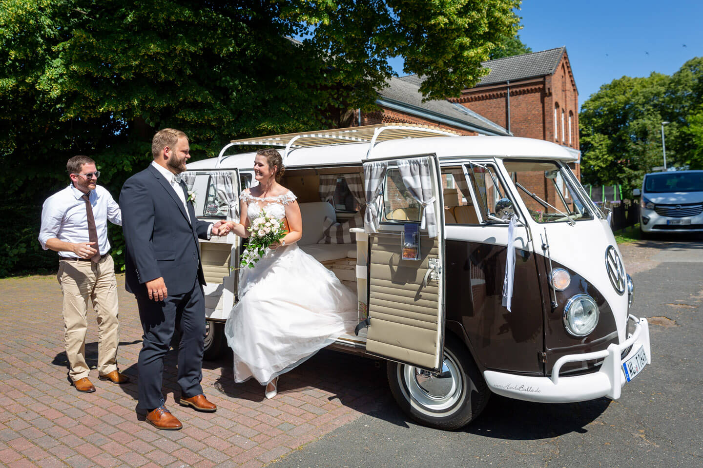 Hochzeitspaar steigt aus VW-Bulli aus