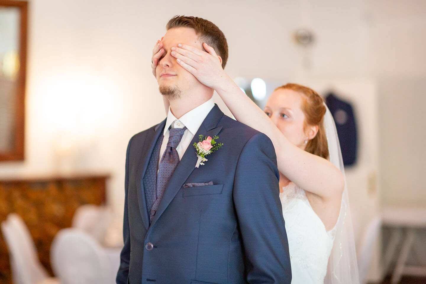 First View - Braut hält Bräutigam die Augen zu.