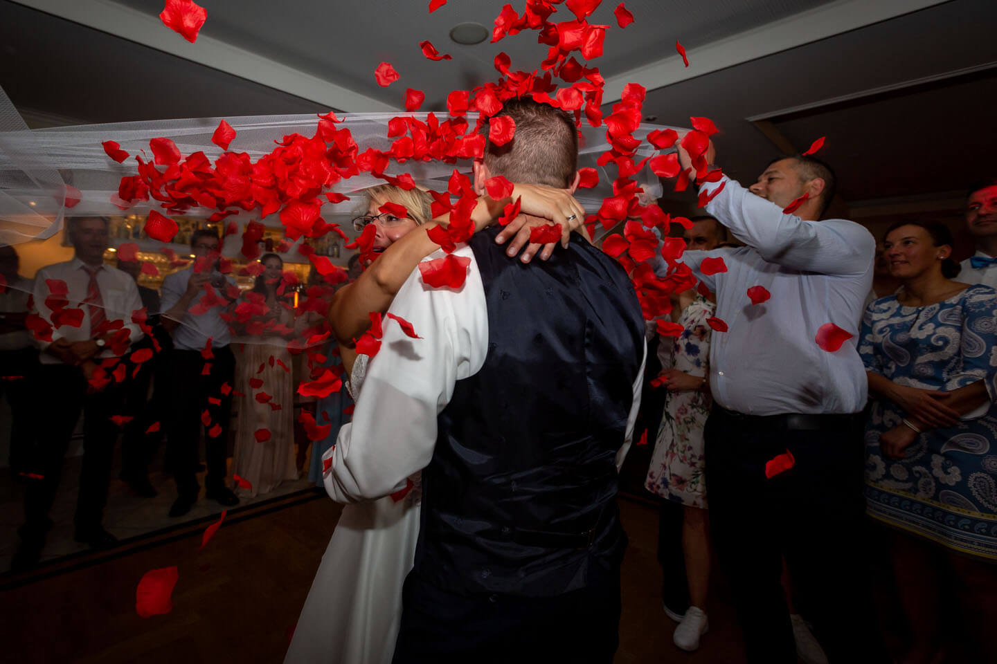 Rosenblätter fallen beim Schleiertanz auf das Hochzeitspaar