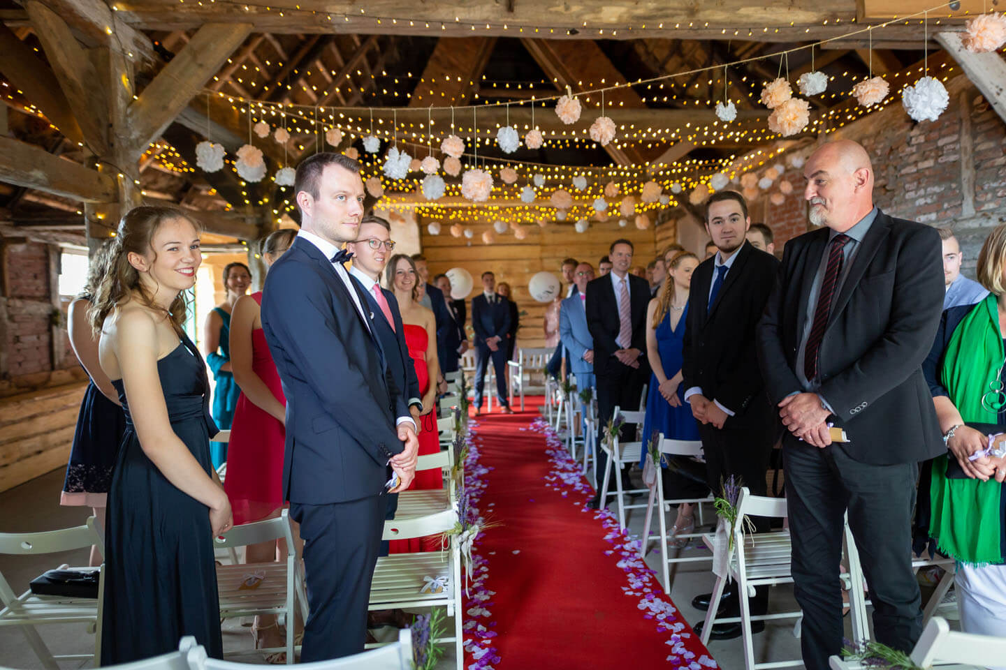 Hochzeitsgäste warten bei einer Scheunenhochzeit auf die Braut.