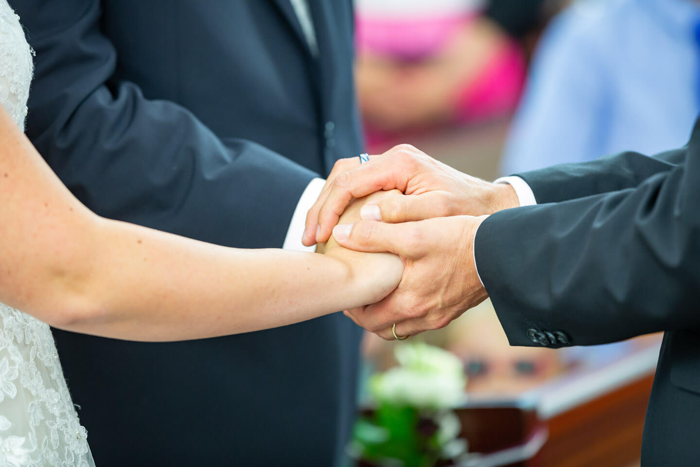 Die Hände von Pastor und Brautpaar während der Trauung