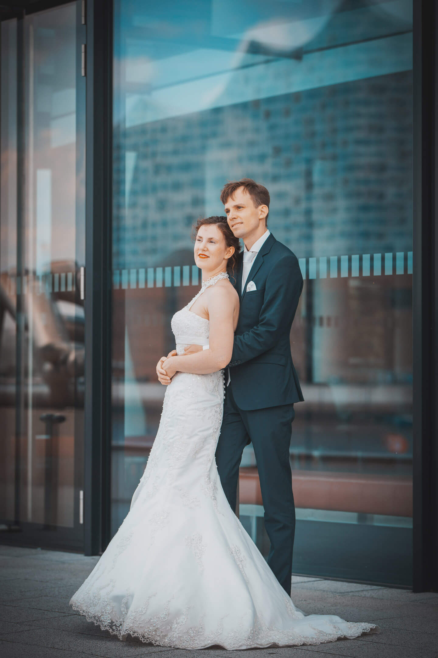 Brautpaar vor Glasfront in der sich die Elphi spiegelt
