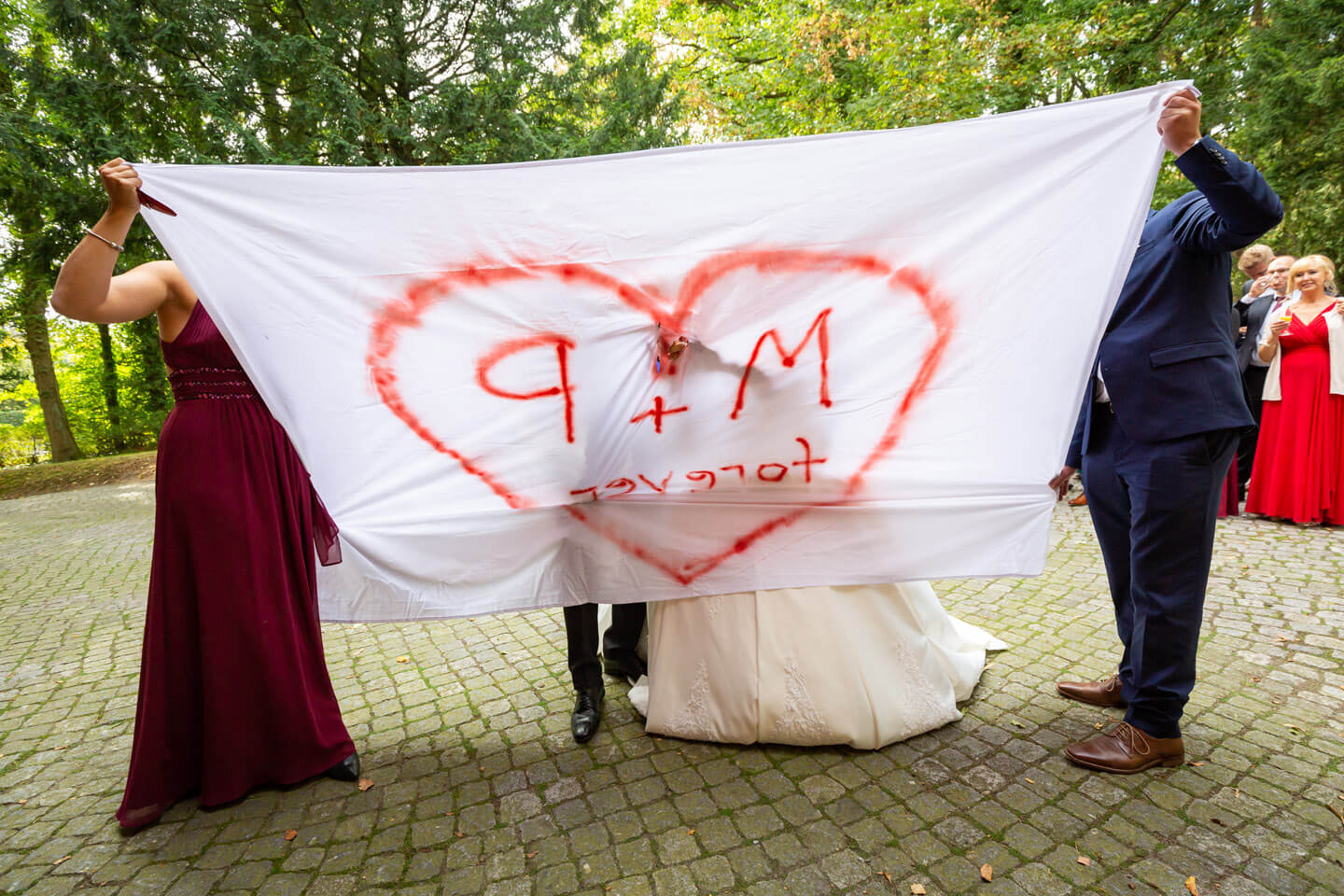 Hochzeitspaar schneidet aufgemaltes Herz aus dem Bettlaken aus